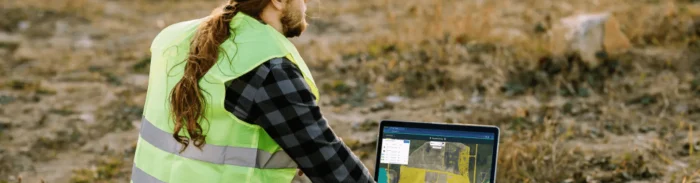 Field engineer using Picterra on laptop outdoors for land monitoring