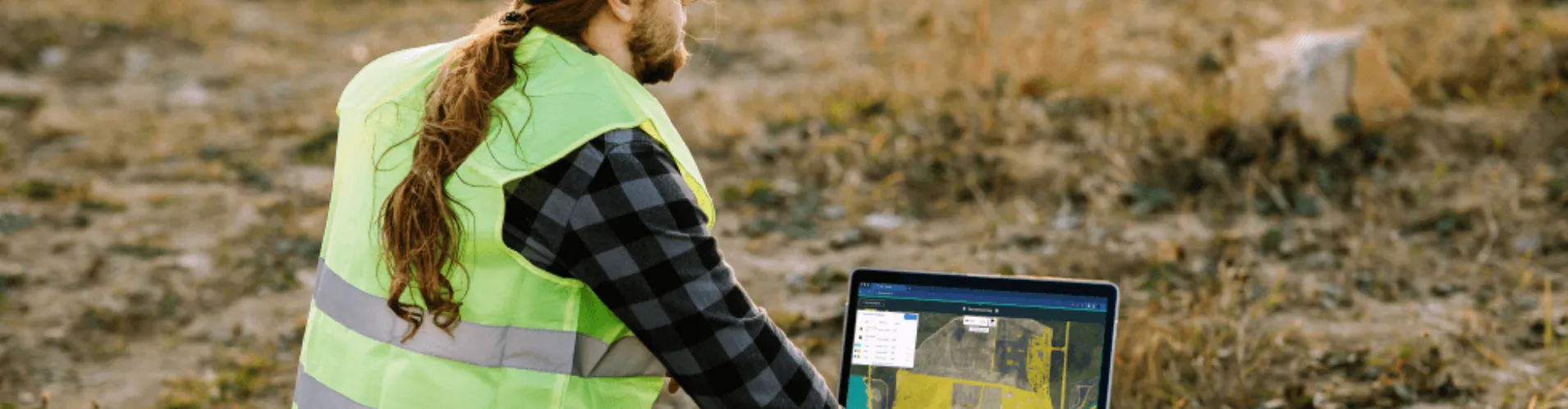 Field engineer using Picterra on laptop outdoors for land monitoring