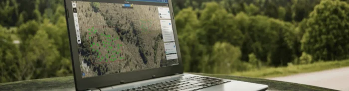 Laptop on outdoor surface showing Picterra platform monitoring vegetation and forest plots
