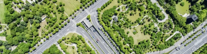Aerial view of urban roads and intersections surrounded by green parks and trees
