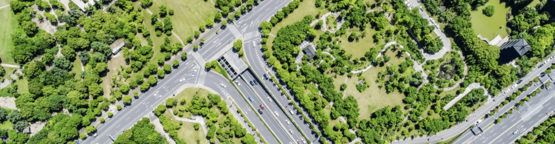 Aerial view of urban roads and intersections surrounded by green parks and trees