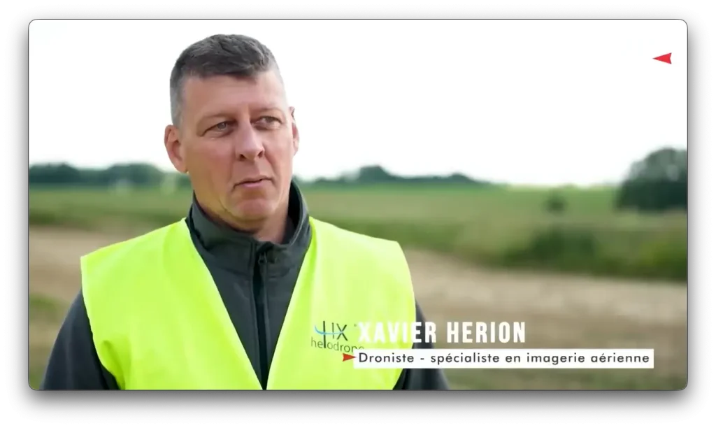 Aerial imaging specialist Xavier Herion standing in an agricultural field wearing a high-visibility vest, introducing drone-based imagery for agricultural monitoring.