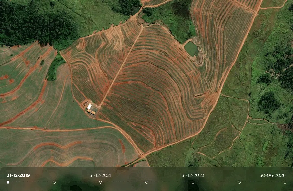 Aerial satellite view of agricultural fields with curved contour rows, surrounding forest, farm buildings, and a small pond, shown with a timeline from 2019 to 2026 to illustrate changes in the landscape and progression toward regenerative agriculture.